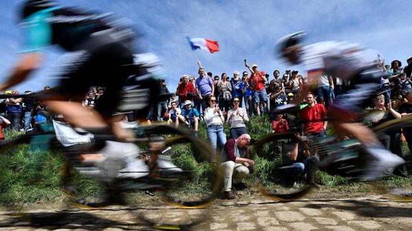 (FILES) In this file photo taken on April 8, 2018 spectators watch cyclists as they drive across cobbled stone during the 116th edition of the Paris-Roubaix one-day classic cycling race, between Compiegne and Roubaix, in Quievy, northern France. - The International Cycling Union (UCI) announced on April 1, 2021, that Paris-Roubaix, the queen of classics, cycle race has been postponed from April 11 to October 3 because of the ongoing coronavirus (Covid-19) pandemic. (Photo by JEFF PACHOUD / AFP)