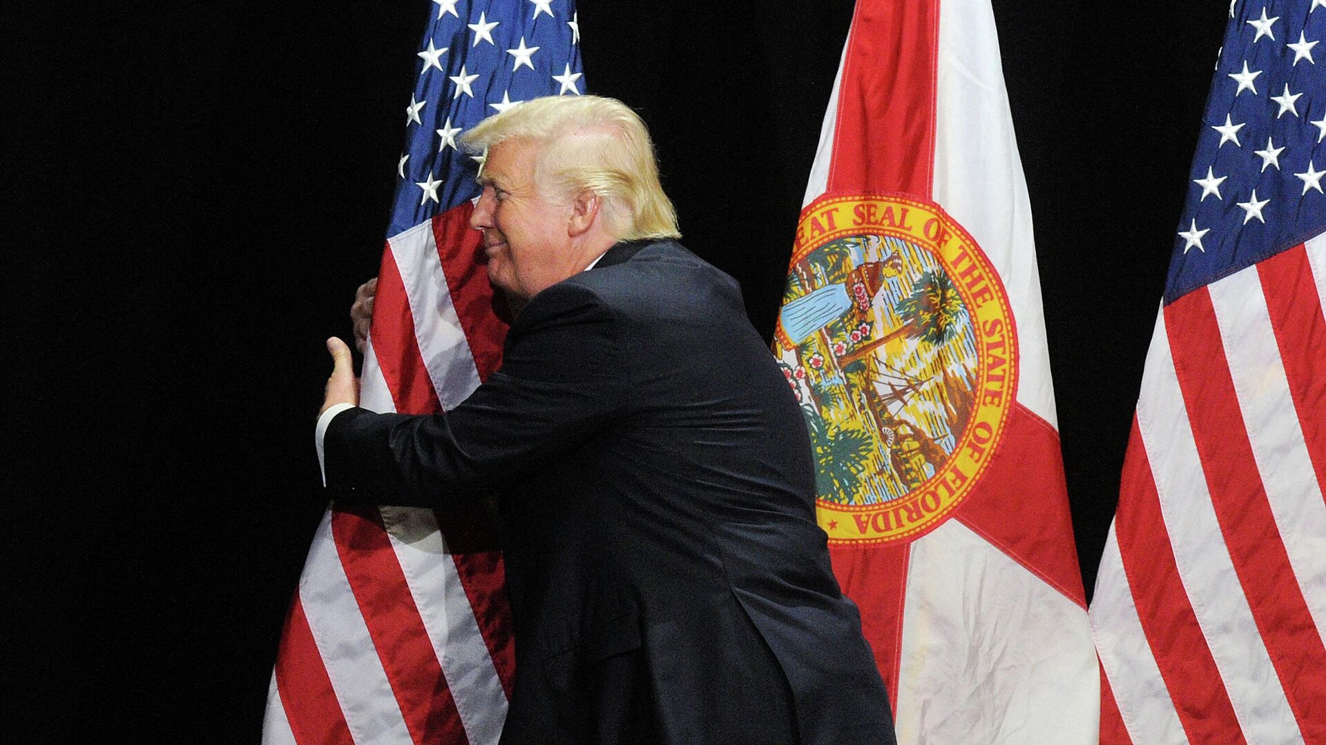 Дональд Трамп обнимает флаг США в штате Флорида  - РИА Новости, 1920, 03.04.2021