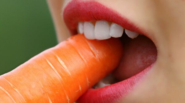 Девушка ест морковку