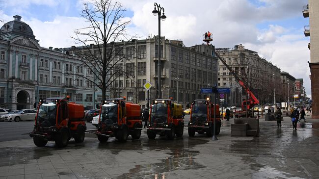 Автомобили коммунальной службы производят мытье асфальтового покрытия на Тверской улице в Москве