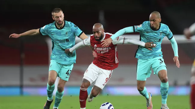 Arsenal's French striker Alexandre Lacazette (C) holds off Liverpool's English defender Nathaniel Phillips (L) and Liverpool's Brazilian midfielder Fabinho (R) during the English Premier League football match between Arsenal and Liverpool at the Emirates Stadium in London on April 3, 2021. (Photo by Adam Davy / POOL / AFP) / RESTRICTED TO EDITORIAL USE. No use with unauthorized audio, video, data, fixture lists, club/league logos or 'live' services. Online in-match use limited to 120 images. An additional 40 images may be used in extra time. No video emulation. Social media in-match use limited to 120 images. An additional 40 images may be used in extra time. No use in betting publications, games or single club/league/player publications. / 
