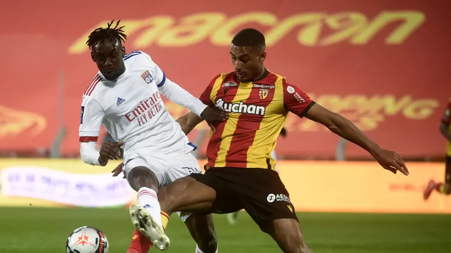 Lens' French defender Loic Bade (R) and Lyon's Cameroonian forward Karl Toko Ekambi fight for the ball during the French L1 football match between Lens and Lyon at the Bollaert Stadium in Lens, on April 3, 2021. (Photo by FRANCOIS LO PRESTI / AFP)