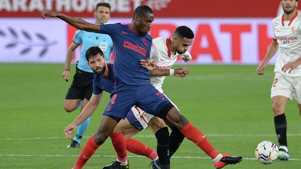 Atletico Madrid's French midfielder Geoffrey Kondogbia (L) challenges Sevilla's Moroccan forward Youssef En-Nesyri during the Spanish League football match between Sevilla FC and Club Atletico de Madrid at the Ramon Sanchez Pizjuan stadium in Seville on April 4, 2021. (Photo by CRISTINA QUICLER / AFP)