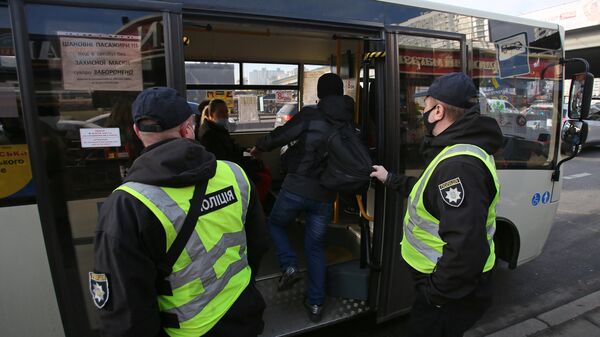 Сотрудники полиции проверяют наличие у пассажиров спецпропусков для проезда на общественном транспорте на одной из остановок в Киеве