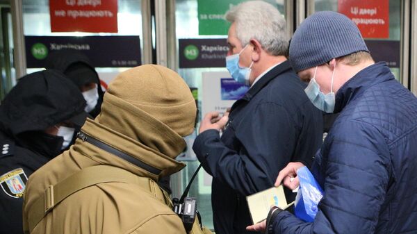 Сотрудники полиции проверяют наличие у пассажиров спецпропусков для проезда на общественном транспорте на одной из станций метро в Киеве