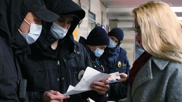 Сотрудники полиции проверяют наличие у девушки спецпропуска для проезда на общественном транспорте на одной из станций метро в Киев