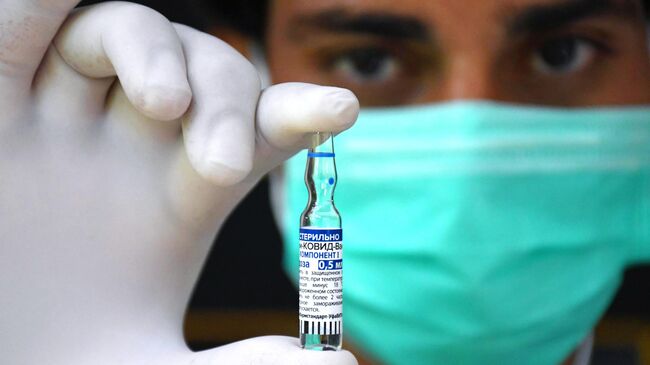 Медицинский работник держит в руках ампулу с российским препаратом от коронавирусной инфекции Гам-Ковид-Вак (Спутник V) 
