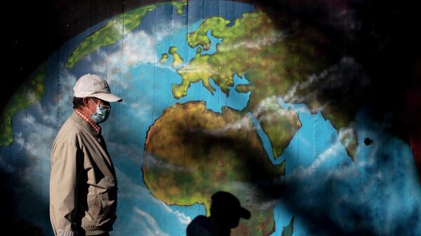 Мужчина в защитной маске проходит мимо граффити с изображением глобуса во время пандемии коронавируса в мире 