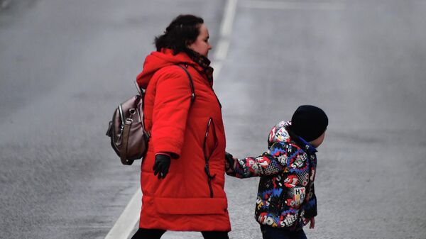 Женщина с ребенком идут по пешеходному переходу