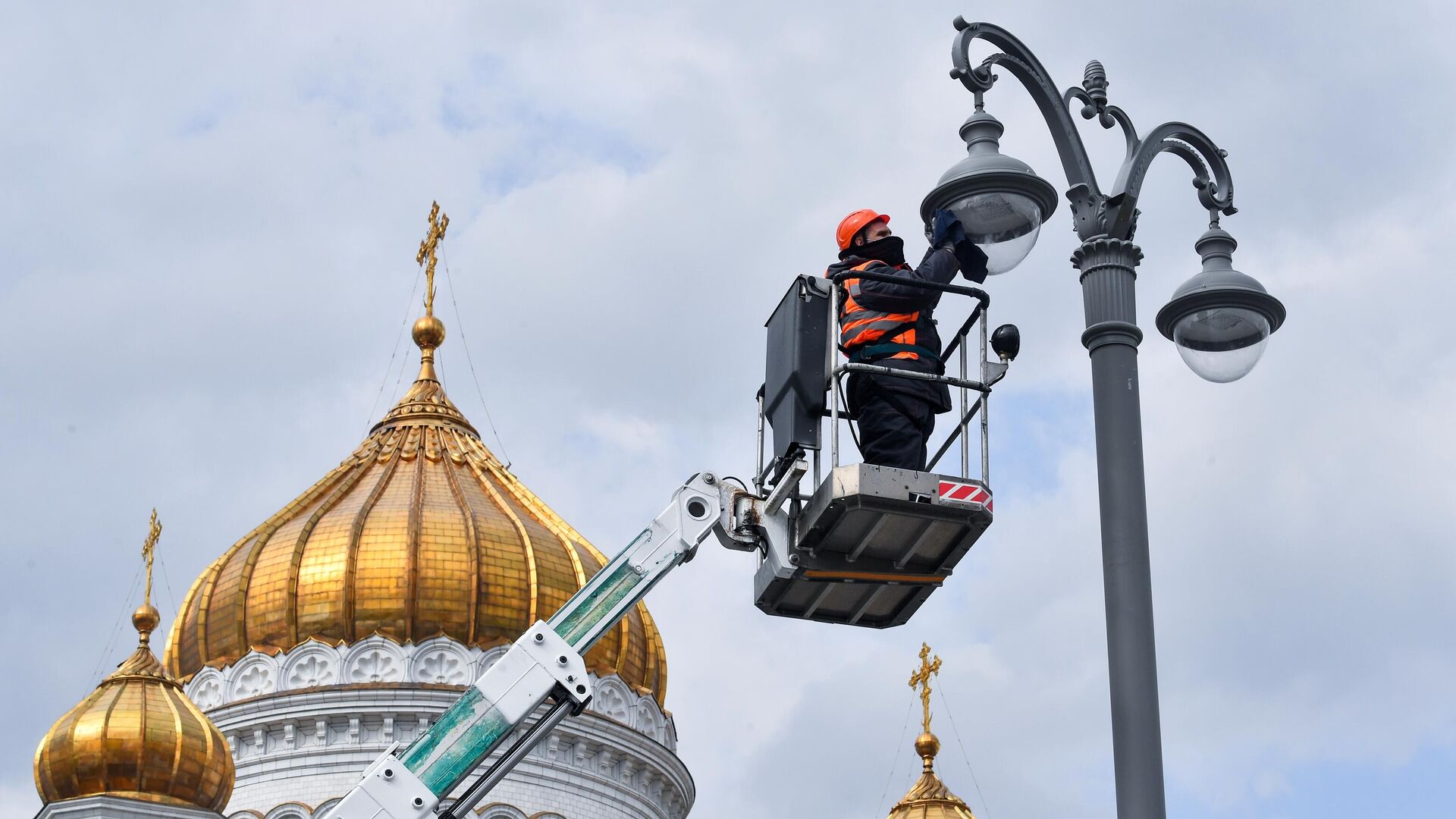 Сотрудник коммунальной службы протирает плафон фонаря наружного освещения на Пречистенской набережной в Москве - РИА Новости, 1920, 07.04.2021