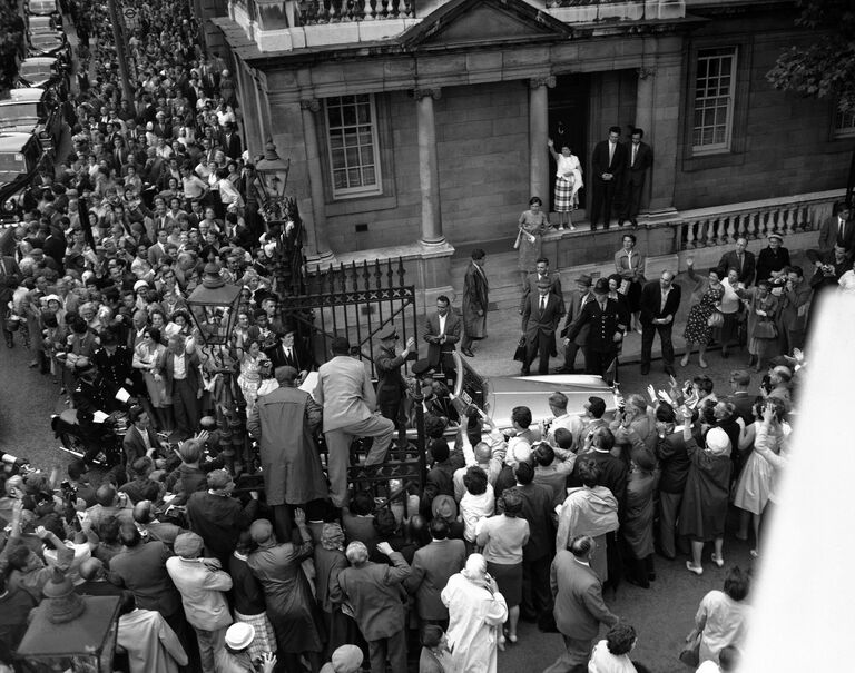 Люди залезают на ворота у советского посольства в Лондоне, 11 июля 1961 года, чтобы лучше разглядеть российского космонавта Юрия Гагарина, который стоит в открытом Rolls-Royce. Он приехал в Лондон на советскую выставку