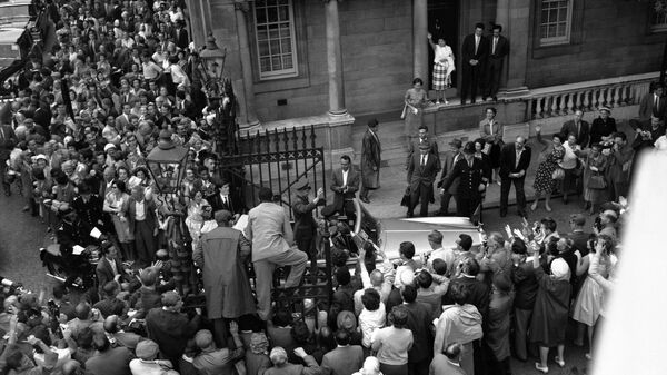 Люди залезают на ворота у советского посольства в Лондоне, 11 июля 1961 года, чтобы лучше разглядеть российского космонавта Юрия Гагарина, который стоит в открытом Rolls-Royce. Он приехал в Лондон на советскую выставку