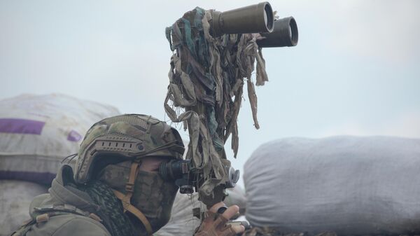 Военнослужащий украинских вооруженных сил осматривает в бинокль территорию на боевых позициях на линии разделения близ города Донецк