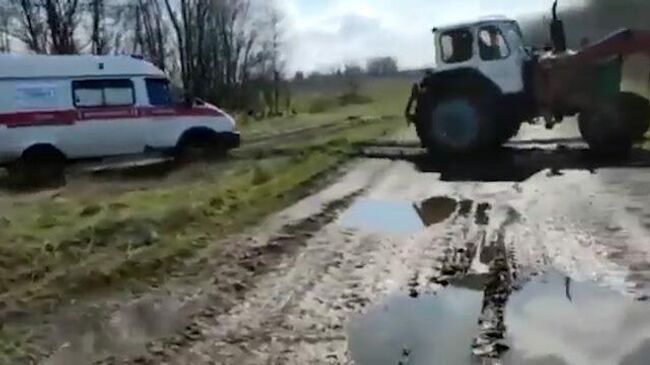 Трактор вытаскивает застрявшую машину скорой помощи