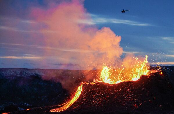 Вертолет пролетает над лавой, вытекающей из трещины вулкана Фаградальсфьядль на полуострове Рейкьянес в Исландии