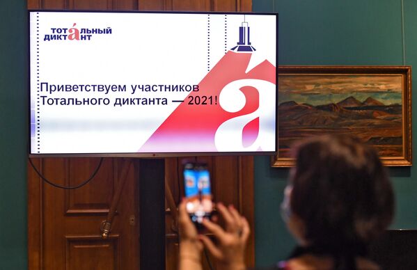 Девушка фотографирует экран во время тотального диктанта в Приморской государственной картинной галерее во Владивостоке