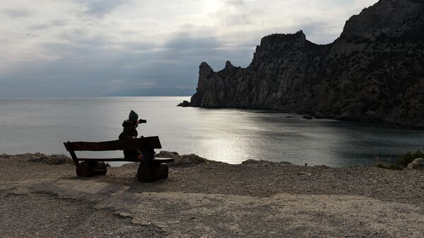 Девушка фотографирует мыс Капчик рядом с поселком Новый свет в Крыму