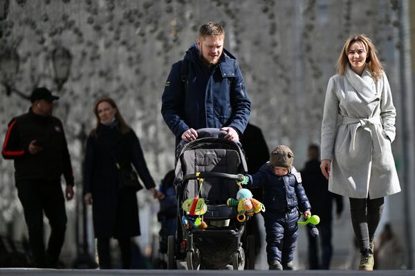 Молодые люди с ребёнком во время прогулки на улице Никольская в Москве