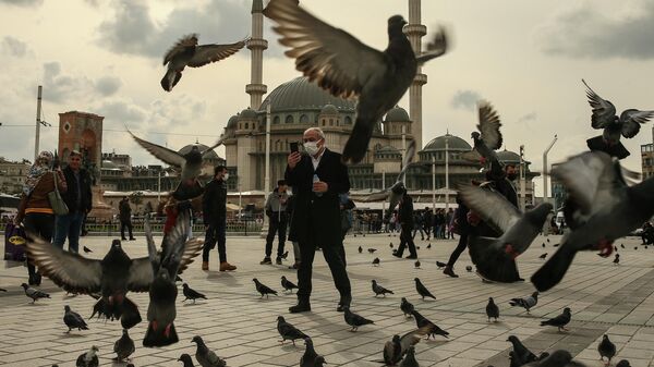 Мужчина кормит голубей на площади Таксим в Стамбуле