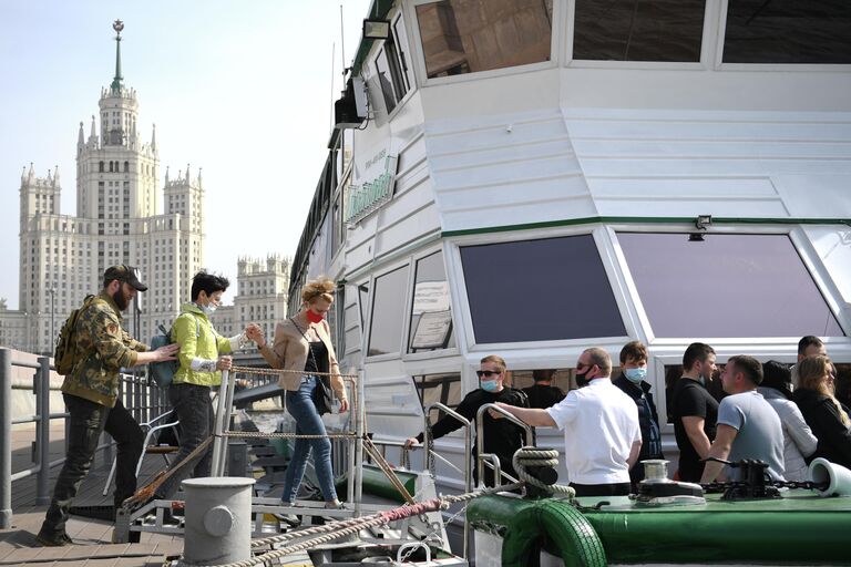 Пассажиры на причале Устьинский мост во время посадки на теплоход для речной прогулки по Москве-реке.