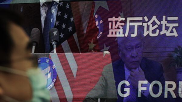 Мужчина возле экрана, демонстрирующего, встречу делегатов Китая и США на форуме Лантинга