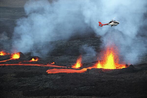 Вертолет пролетает над вулканом Питон-де-ла-Фурнез во время его извержения на острове Реюньон в Индийском океане