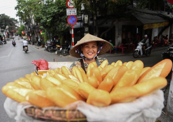 Уличная продавщица везет на велосипеде багеты для продажи в Ханое