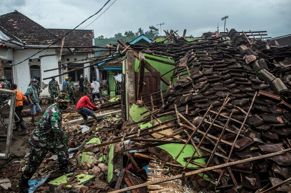 Индонезийские солдаты и жители проверяют поврежденные дома после землетрясения в Маланге, Восточная Ява