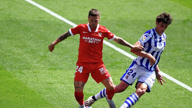 Sevilla's Argentinian forward Papu Gomez (L) challenges Real Sociedad's French defender Robin Le Normand during the Spanish League football match between Real Sociedad and Sevilla FC at the Anoeta stadium in San Sebastian on April 18, 2021. (Photo by ANDER GILLENEA / AFP)