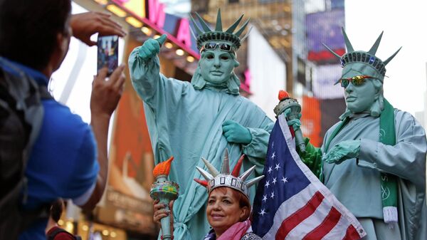 Туристы фотографируются с мужчинами, одетым в костюмы Статуи Свободы, на Таймс-сквер в Нью-Йорке, США