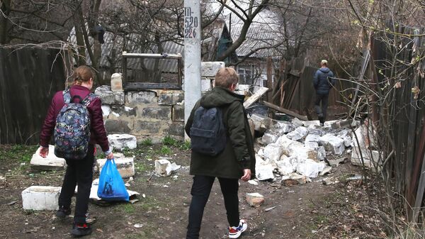 Школьники идут по дороге мимо строения, которое было разрушено в результате утреннего обстрела Горловки