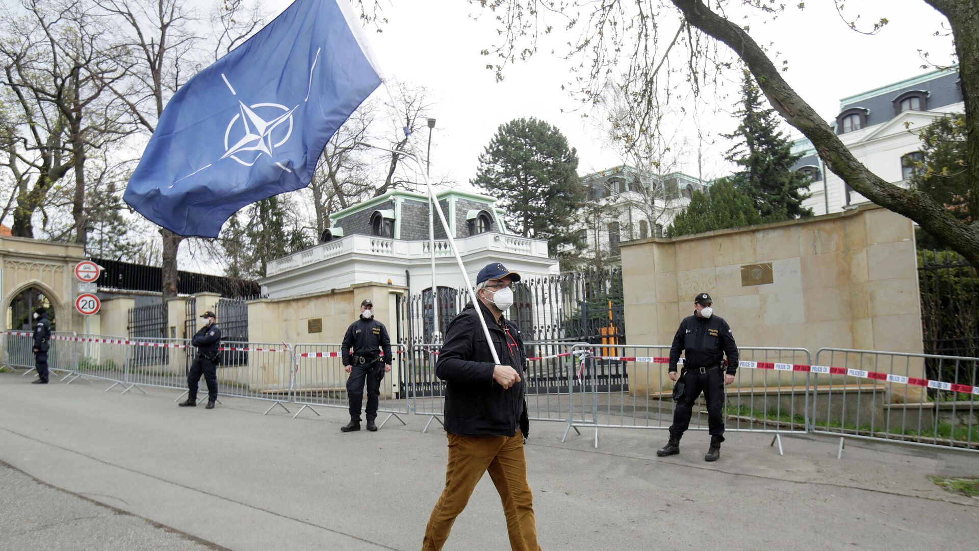 Мужчина с флагом НАТО напротив Российского посольства в Праге, во время акции протеста, связанной с объявленной причастностью России ко взрывам на складах боеприпасов в деревне Врбетице в 2014 году - РИА Новости, 1920, 05.05.2021