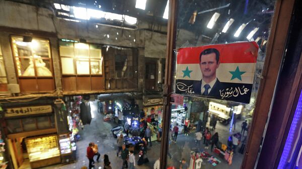 Плакат с изображением президента Сирии Башара Асада на рынке в Дамаске