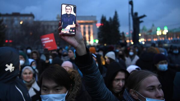 Участник несанкционированной акции в поддержку Алексея Навального держит смартфон с фотографией А. Навального на площади Ленина в Новосибирске