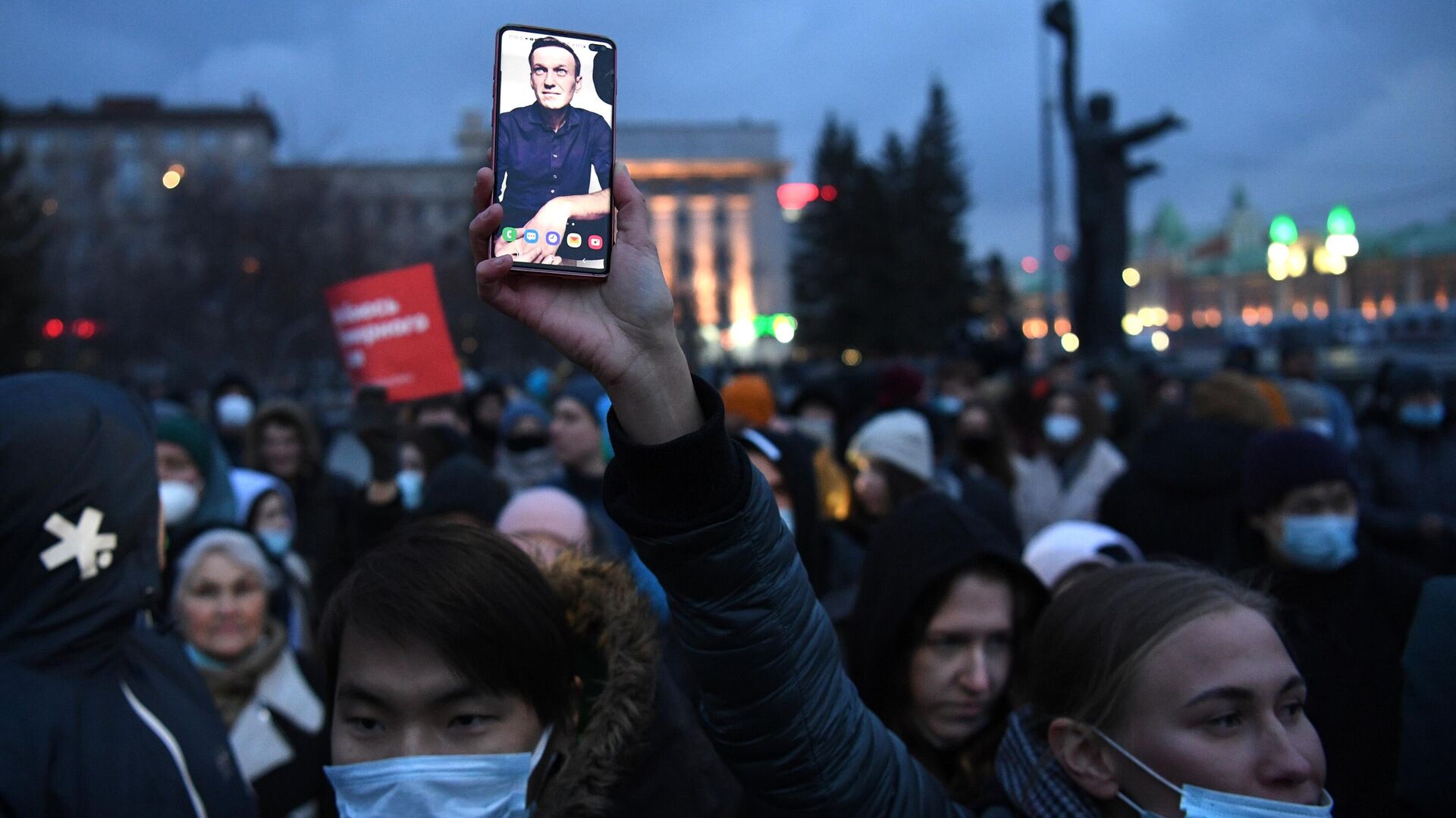 Участник несанкционированной акции в поддержку Алексея Навального держит смартфон с фотографией А. Навального на площади Ленина в Новосибирске - РИА Новости, 1920, 22.04.2021