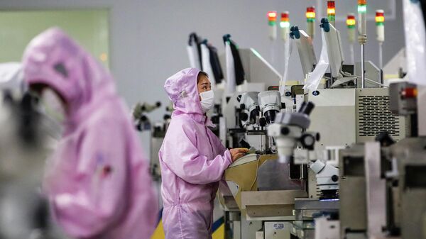 Китайские сотрудники в масках и защитных костюмах работают на производстве смарт-чипов