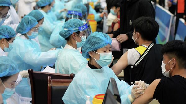 Медицинские работники во время вакцинации пациентов от коронавируса в университете в Циндао