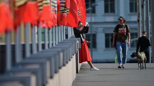 Девушка фотографируется у флагов, установленных к празднованию Дня Победы, на Москворецкой набережной в Москве