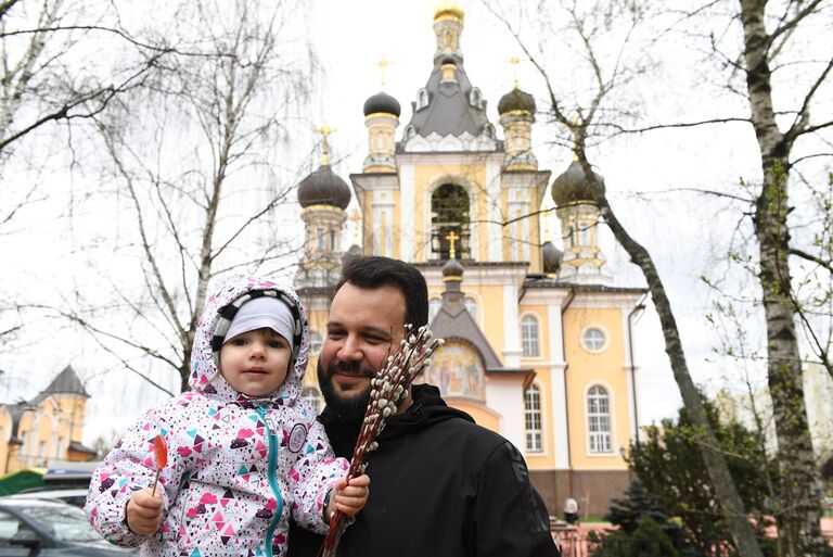 Прихожанин с ребенком у храма Сретения Господня в Жулебино в день празднования Входа Господня в Иерусалим