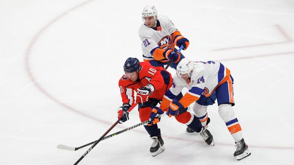 Apr 27, 2021; Washington, District of Columbia, USA; Washington Capitals right wing Daniel Sprong (10) passes the puck as New York Islanders right wing Kyle Palmieri (21) and Islanders center Travis Zajac (14) defend in the second period at Capital One Arena. Mandatory Credit: Geoff Burke-USA TODAY Sports