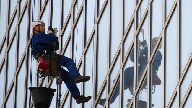 Промышленный альпинист моет фасад высотного здания