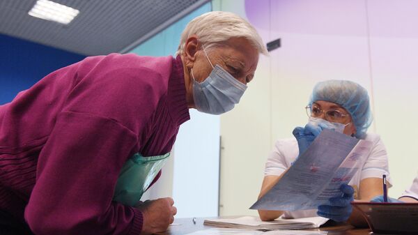 Медработник показывает пожилой женщине сертификат о вакцинации от COVID-19