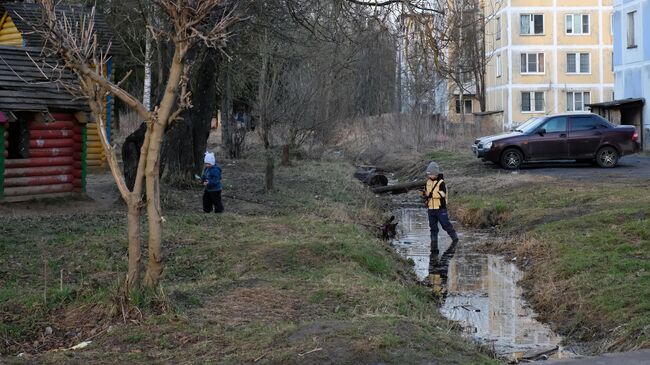 Дети играют в луже рядом с площадкой