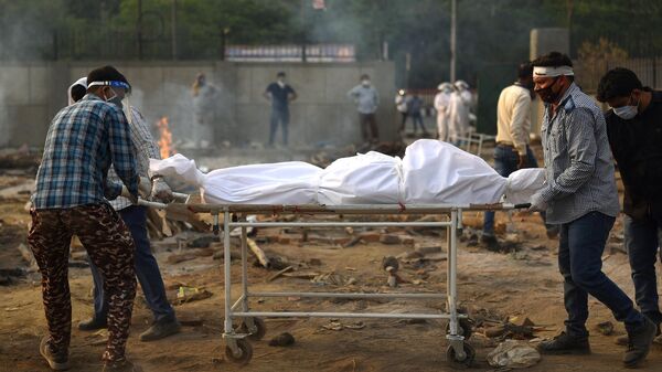 Подготовка тела погибшего к кремации жертв пандемии в Дели