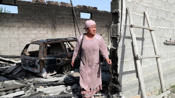 Женщина стоит у сгоревшего строения в приграничном с Таджикистаном селе Максат Лейлекского района Баткенской области
