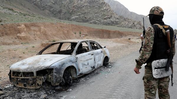 Военнослужащий Киргизии стоит у сгоревшей машины на границе Таджикистана и Киргизии в селе Кок-Таш