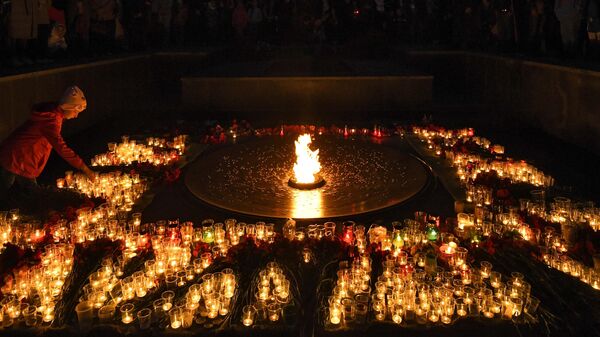 Люди зажигают свечи во время акции Свеча памяти на Монументе Славы в Новосибирске