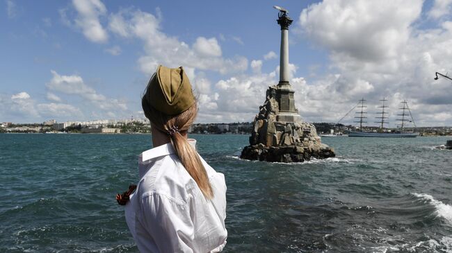 Жительница Севастополя наблюдает за торжественным выходом из Севастопольской бухты фрегата Херсонес во время празднования Дня Победы