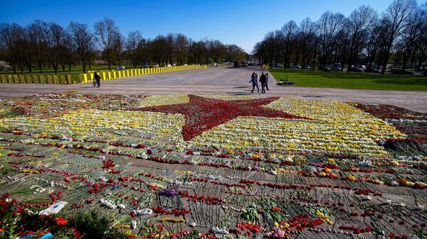 Красная звезда, выложенная волонтерами из цветов, возложенных к памятнику Освободителям в Парке Победы в Риге. Архивное фото