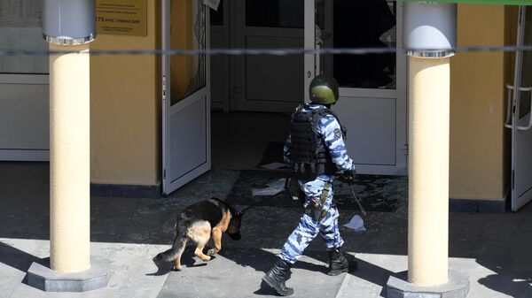 Сотрудник правоохранительных органов со служебной собакой у школы в Казани, где произошла стрельба